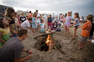 group of kids around bonfire with sticks roasting marshmallows