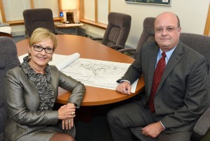man and woman sitting at conference table with blueprints